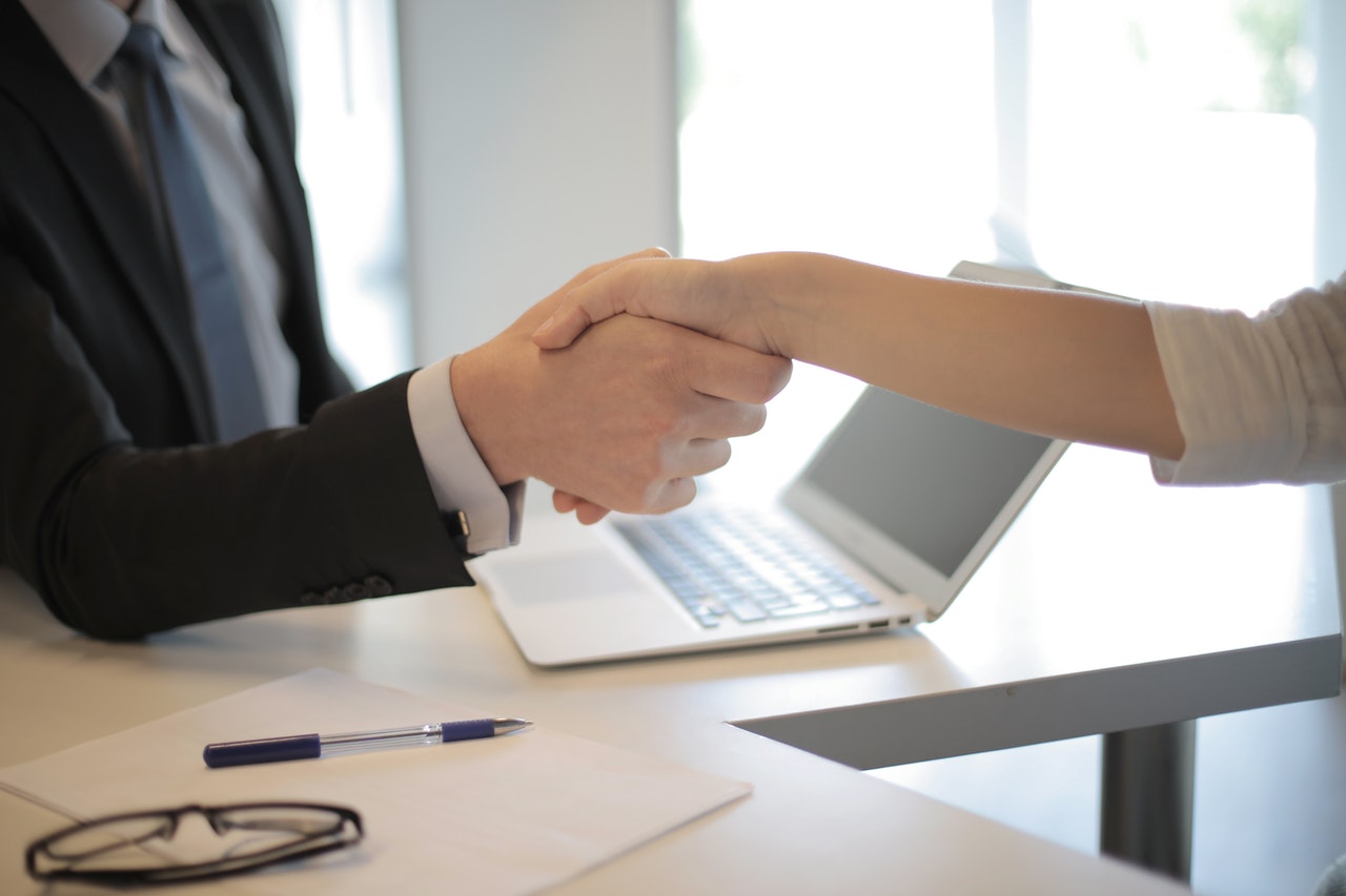 Financial advisor and client shaking hands across table.