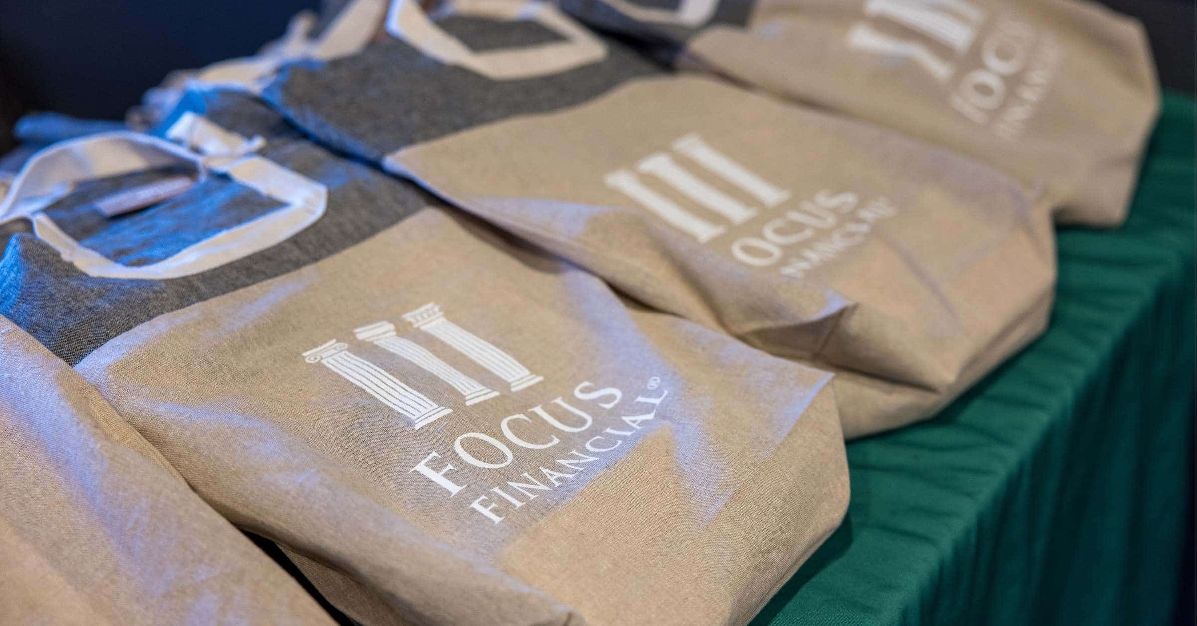 close up of eco-friendly SWAG bags branded focus financial network on a green tablecloth